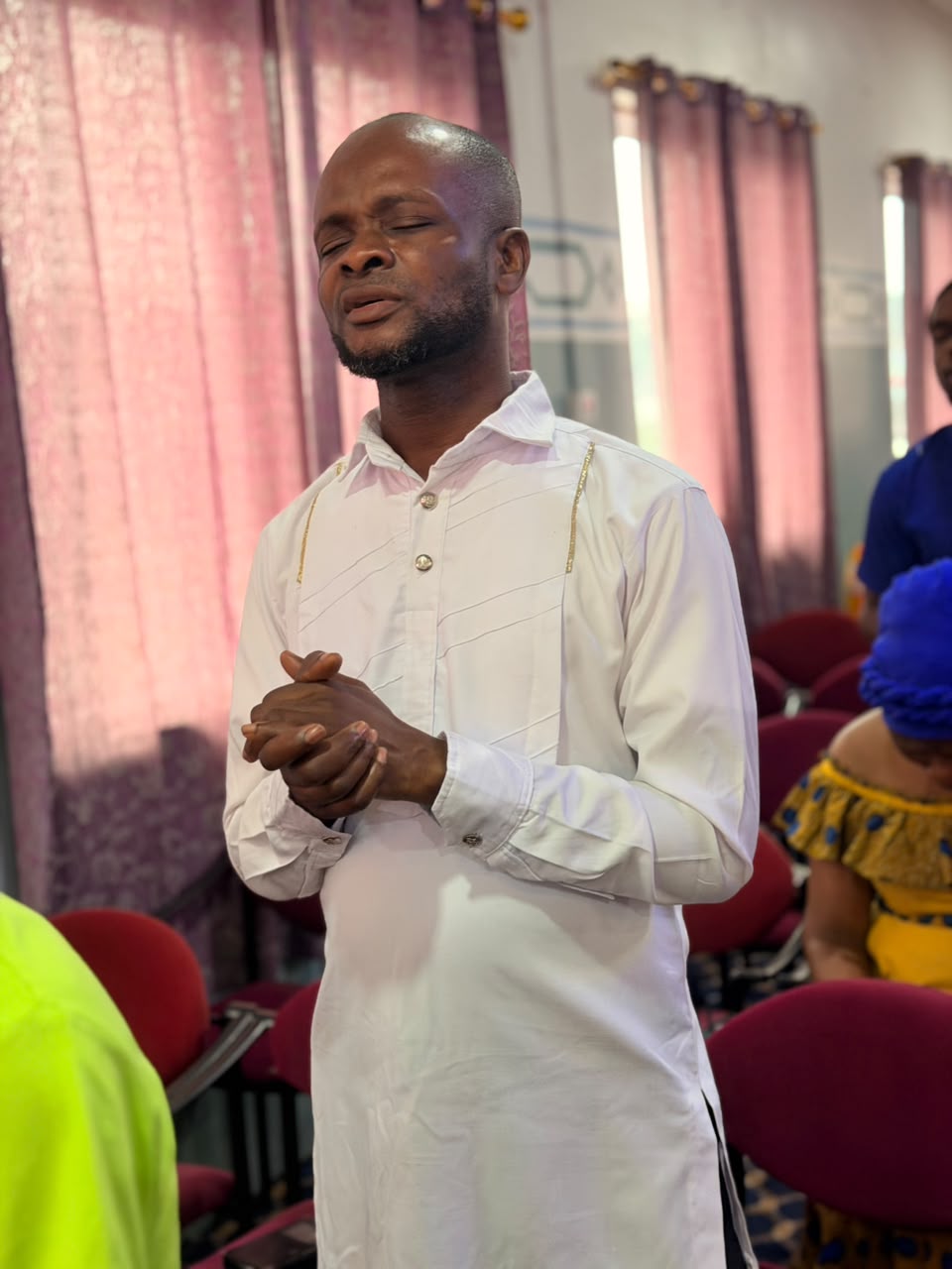 A member with clasped hands lost in prayer